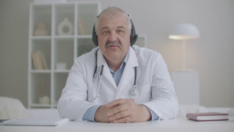 Ein-Männlicher-Arzt-Chattet-Per-Videoanruf-Mit-Kollegen-Oder-Patienten-Und-Sitzt-Während-Der-Coronavirus-Pandemie-In-Der-Fernkommunikation-Der-Klinik